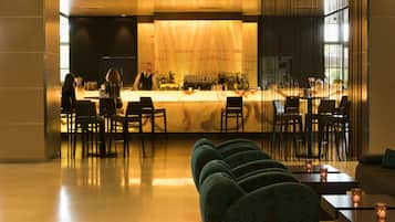 Un espace bar comprenant un comptoir, des tabourets de bar et un coin salon avec des canapés et des tables.