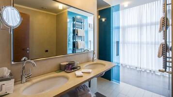 A modern bathroom with two sinks, a large mirror, and a glass shower enclosure.
