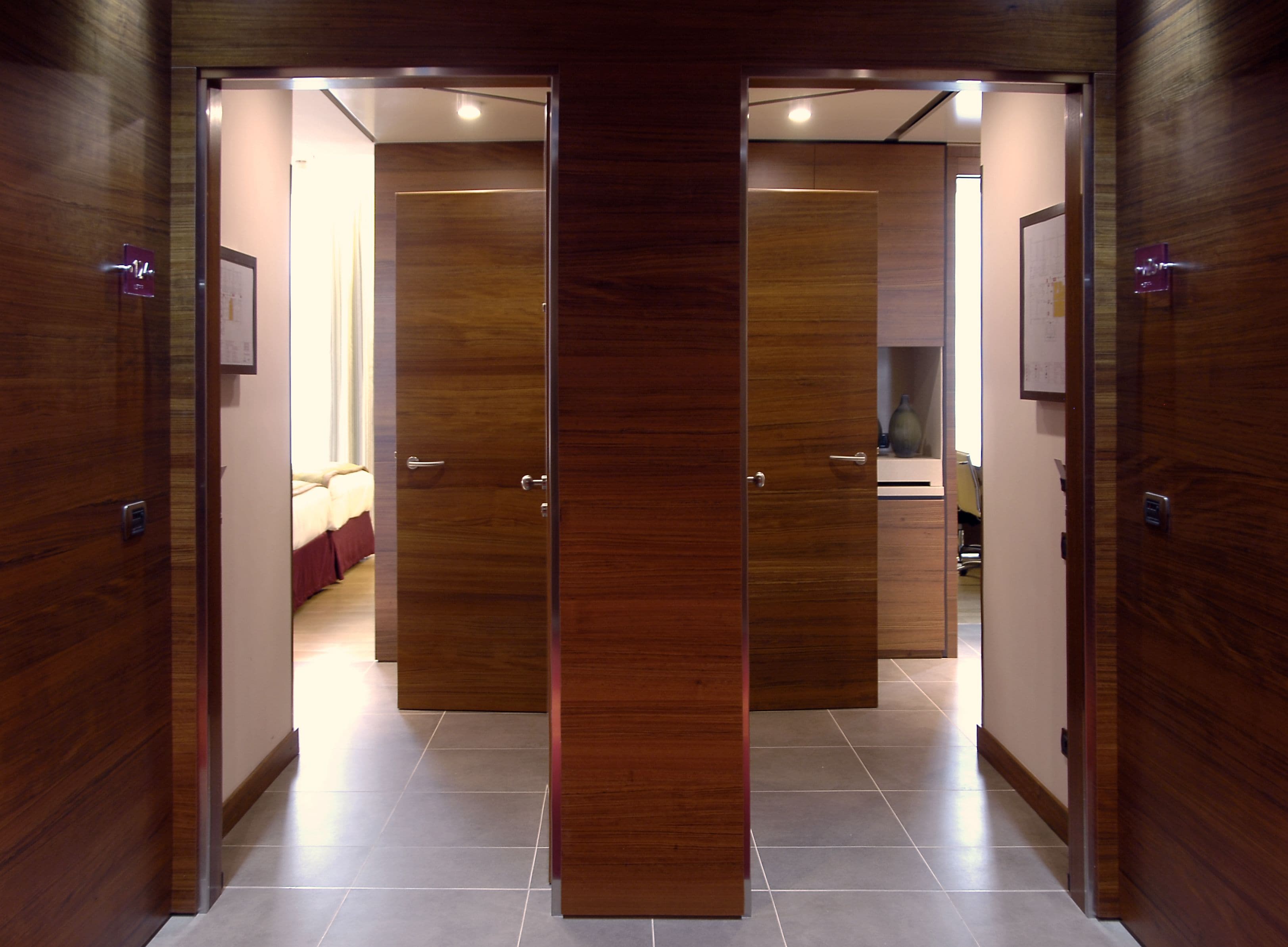 Un pasillo con puertas de madera que dan a un dormitorio y un baño.
