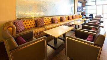 Un restaurant doté d’un long banc rembourré, de tables individuelles et d’un écran de télévision.
