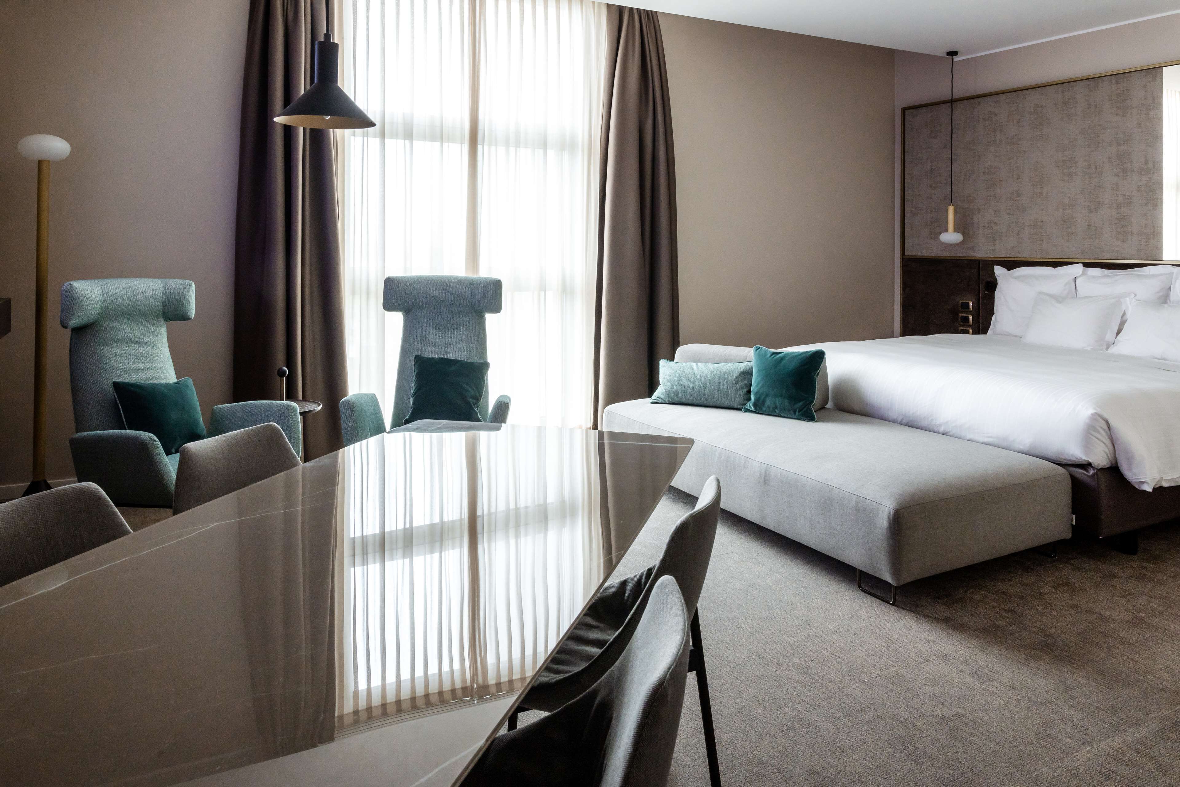 Et hotelværelse med en stor seng, et spisebord og flere stole.