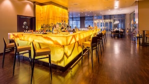 Una zona de bar con mostrador de mármol, varias botellas de licor y taburetes.