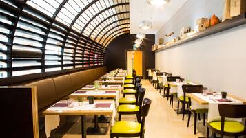 Un restaurante con techo curvo, varias mesas con sillas y una variedad de decoraciones en las paredes.