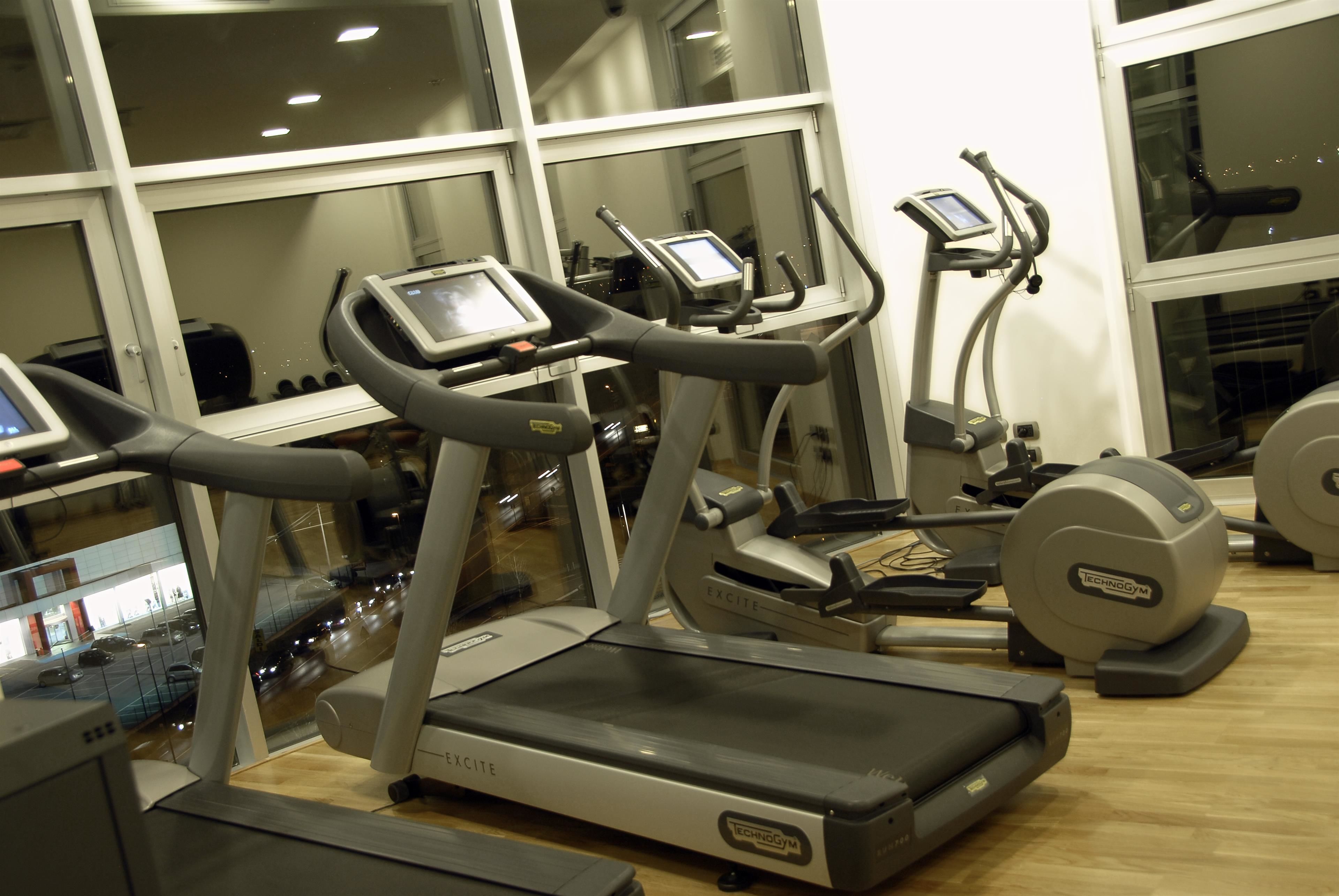 Une salle de sport équipée de tapis de course, de vélos elliptiques et d’appareils de musculation.