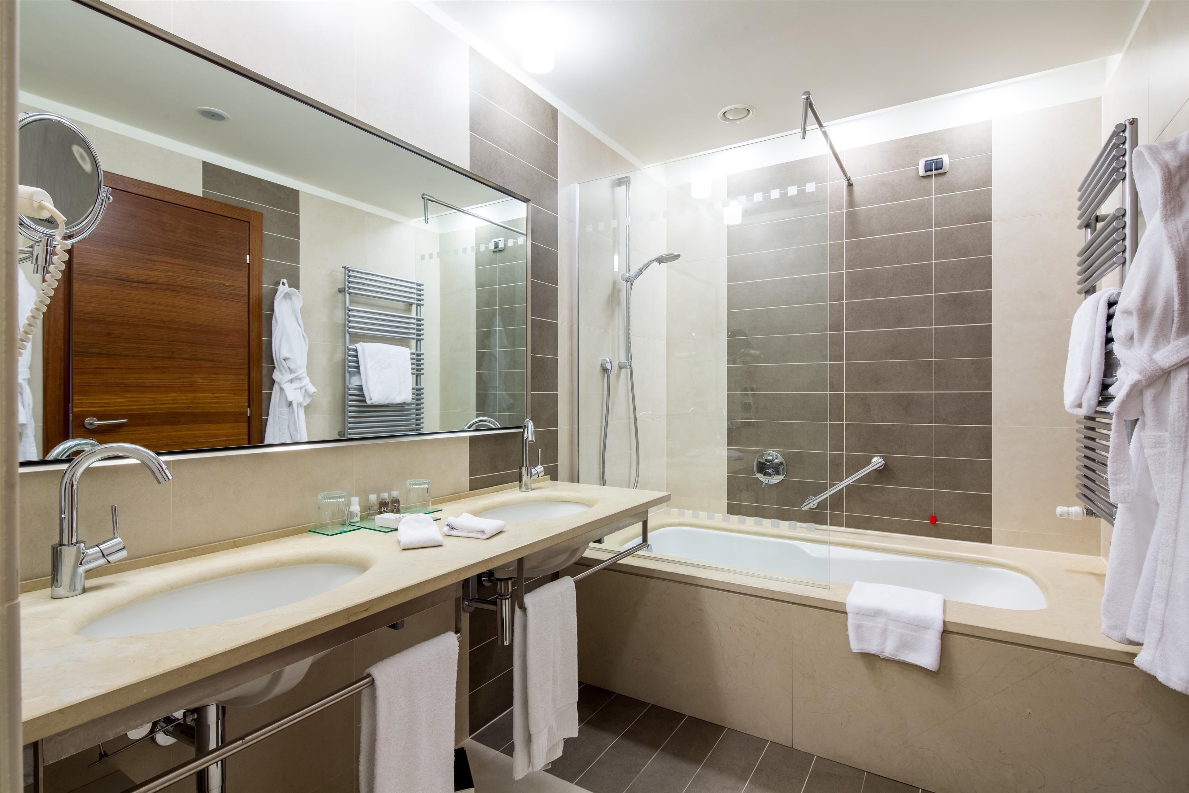 Un baño moderno con dos lavamanos, un espejo grande, ducha y bañera.