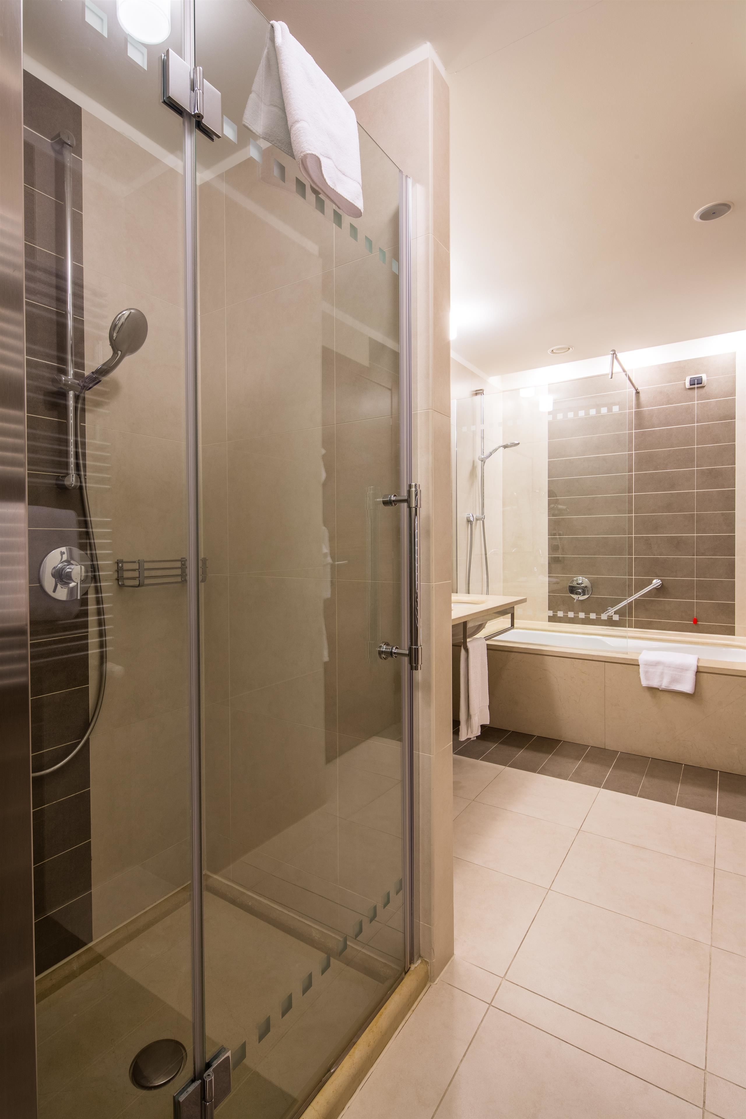 A modern bathroom with a glass-enclosed shower, a separate bathtub, and a vanity with a mirror.