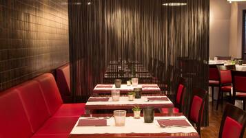Ein Restaurant mit roten Sitzplätzen, Tischen, Menüs, Gläsern und Besteck.