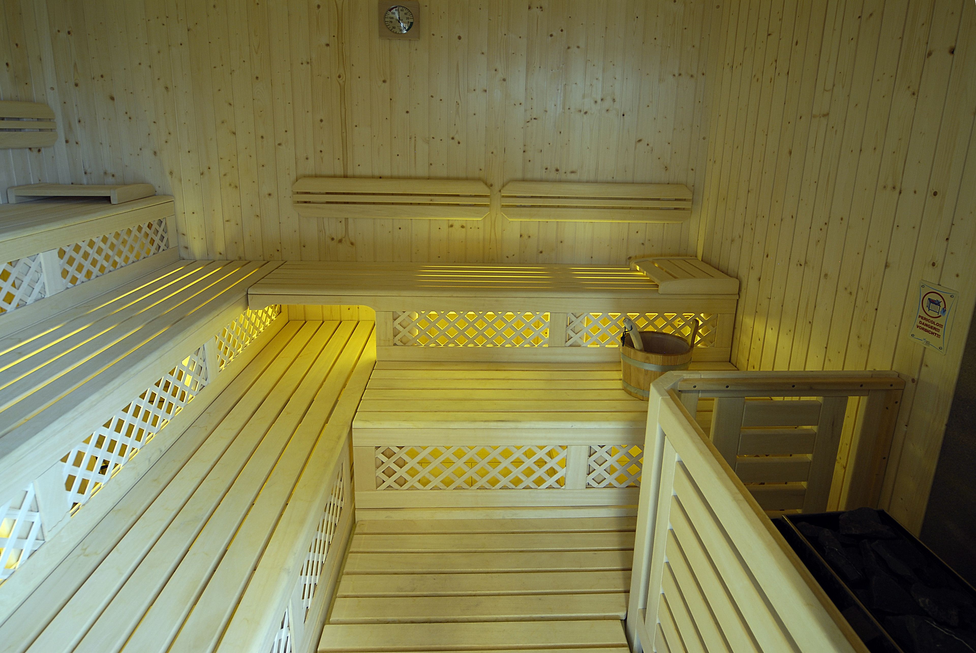 Una sauna con bancos de madera y un reloj en la pared, además de un letrero con un símbolo.