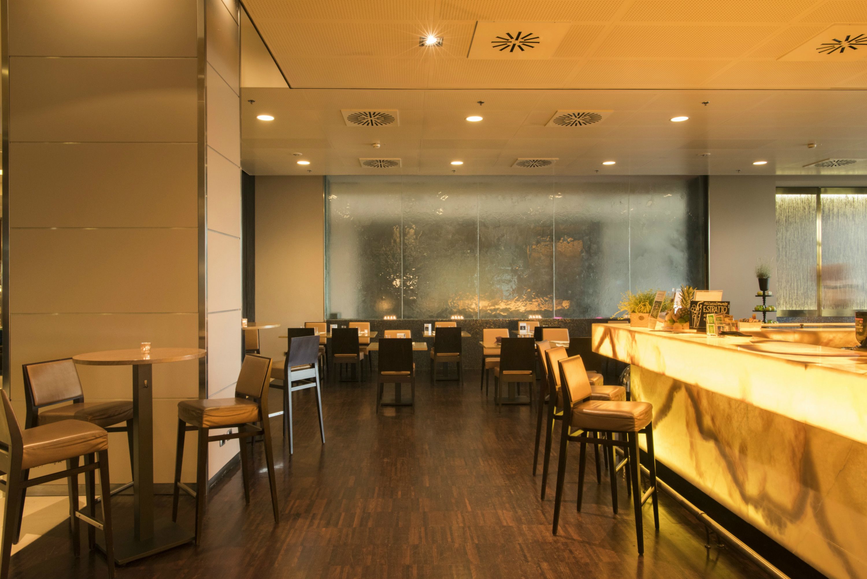 Un restaurante moderno con barra, suelo de madera y un amplio ventanal con vistas.