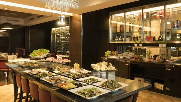 Un bufé con diferentes opciones de comida y una zona de bar con botellas y vasos.