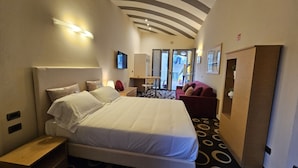 A hotel room with a large bed, a desk, a chair, a red sofa, and a wardrobe. - Residence Select Executive (Florence)