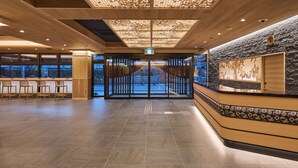 A spacious lobby with a wooden reception desk, a patterned wall, and a view through the glass doors. - Hotel Sugicho (Kyoto)