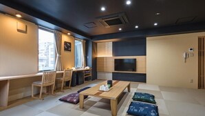 A modern room with a wooden desk, chairs, a table, and a TV. - Hotel Sugicho (Kyoto)