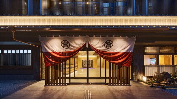 A traditional Japanese building with a wooden exterior, a tiled entrance, and a small garden area with rocks and plants. - Hotel Sugicho (Kyoto)