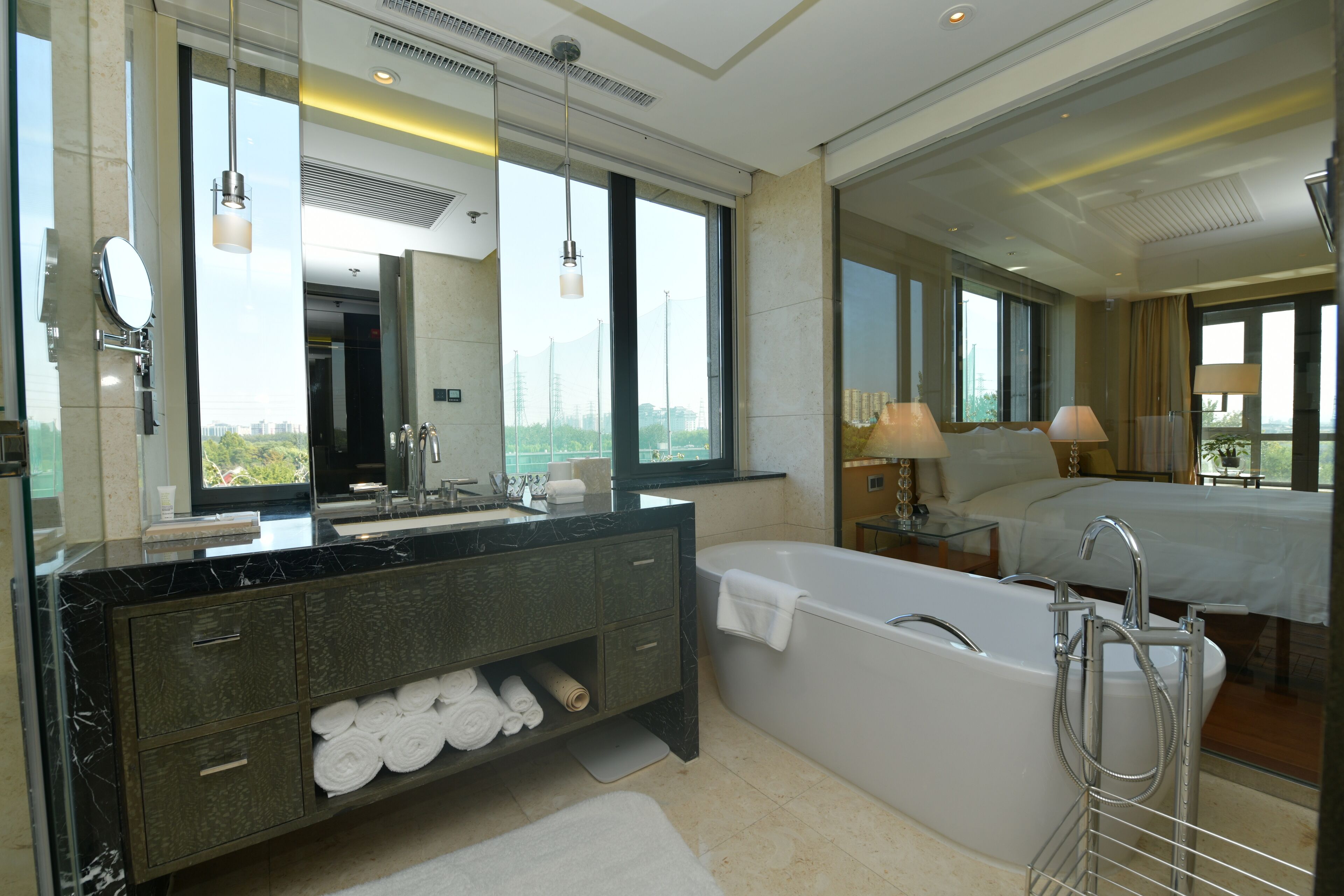 A modern bathroom with a large mirror, a bathtub, and a vanity with towels.