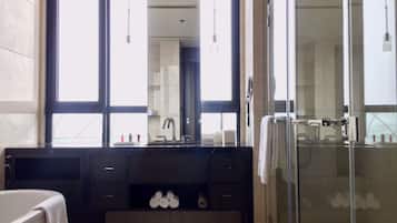 A modern bathroom with a large mirror, a bathtub, a shower area, and a vanity with a sink.
