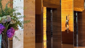 Un vestíbulo moderno con una mesa de vidrio, un jarrón de flores y paneles de madera.