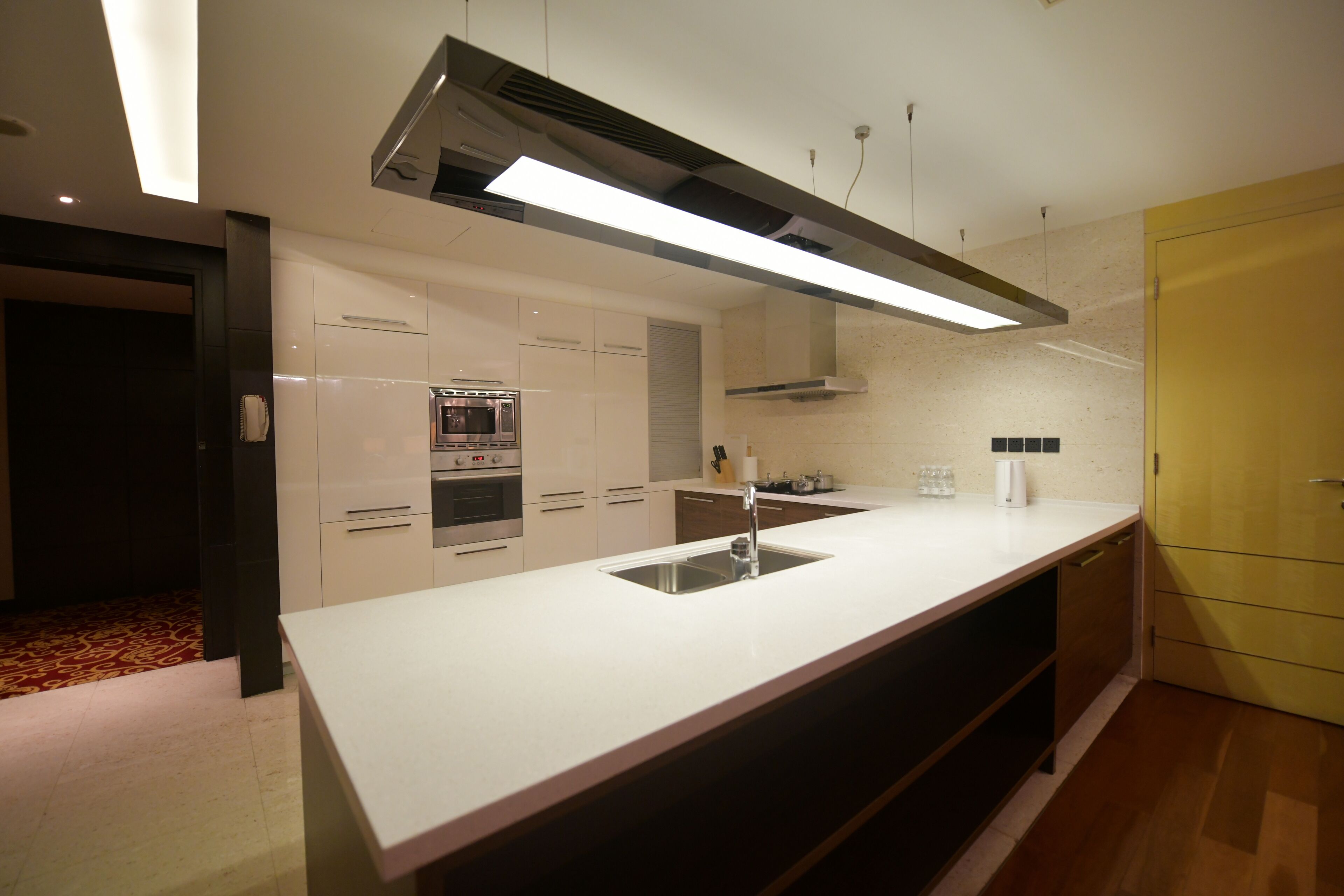 Una cocina moderna con una isla central, electrodomésticos de acero inoxidable y un armario amarillo.