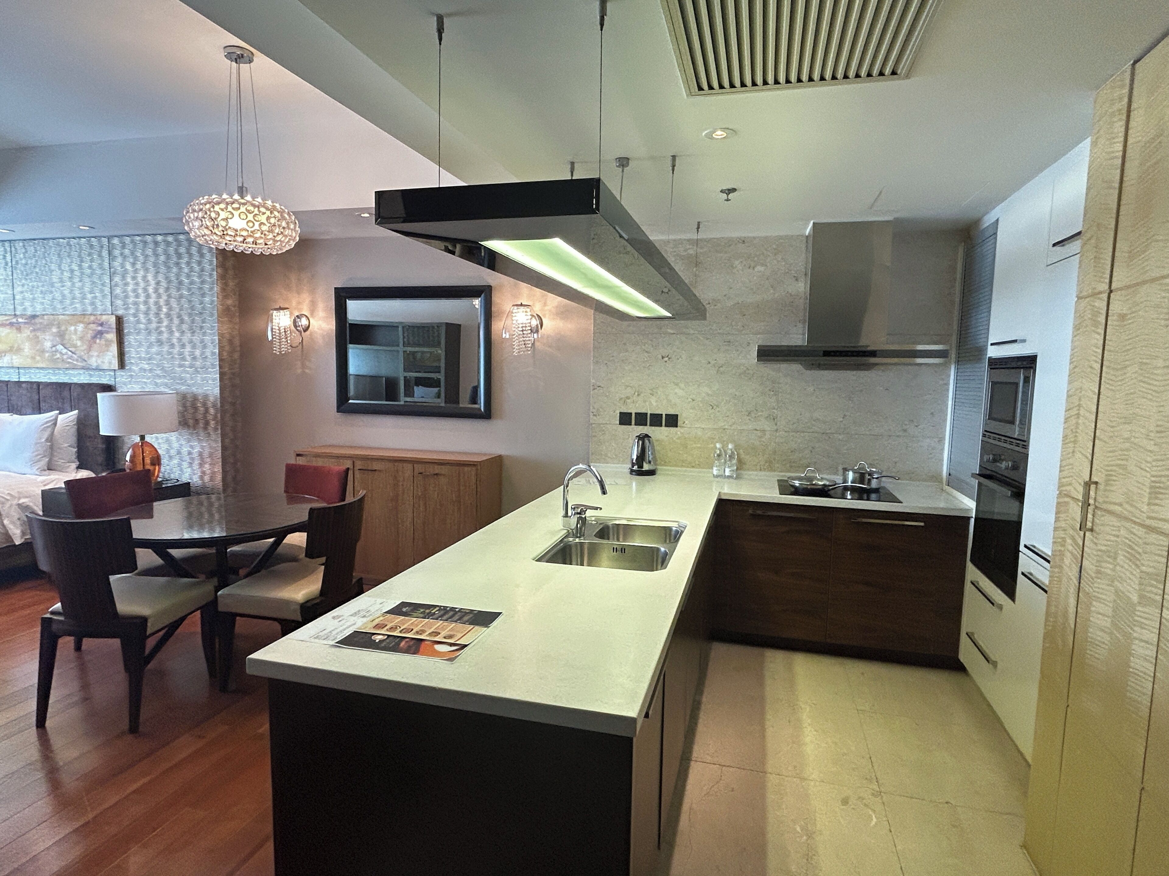 Una cocina moderna con una isla central, horno empotrado y un comedor con mesa y sillas.