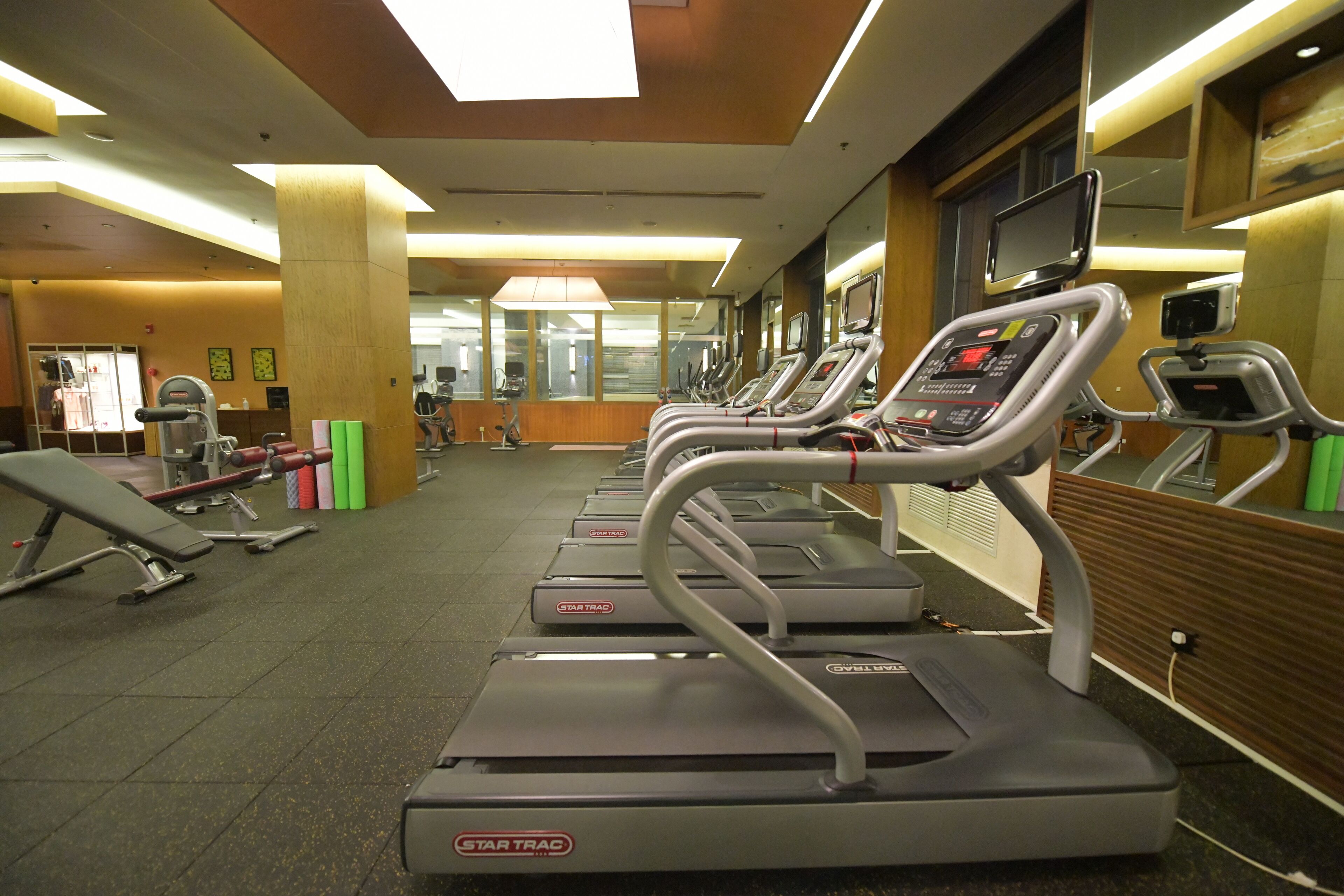 Une salle de sport équipée de tapis de course, d’appareils de musculation et de tapis de sol pour les exercices.