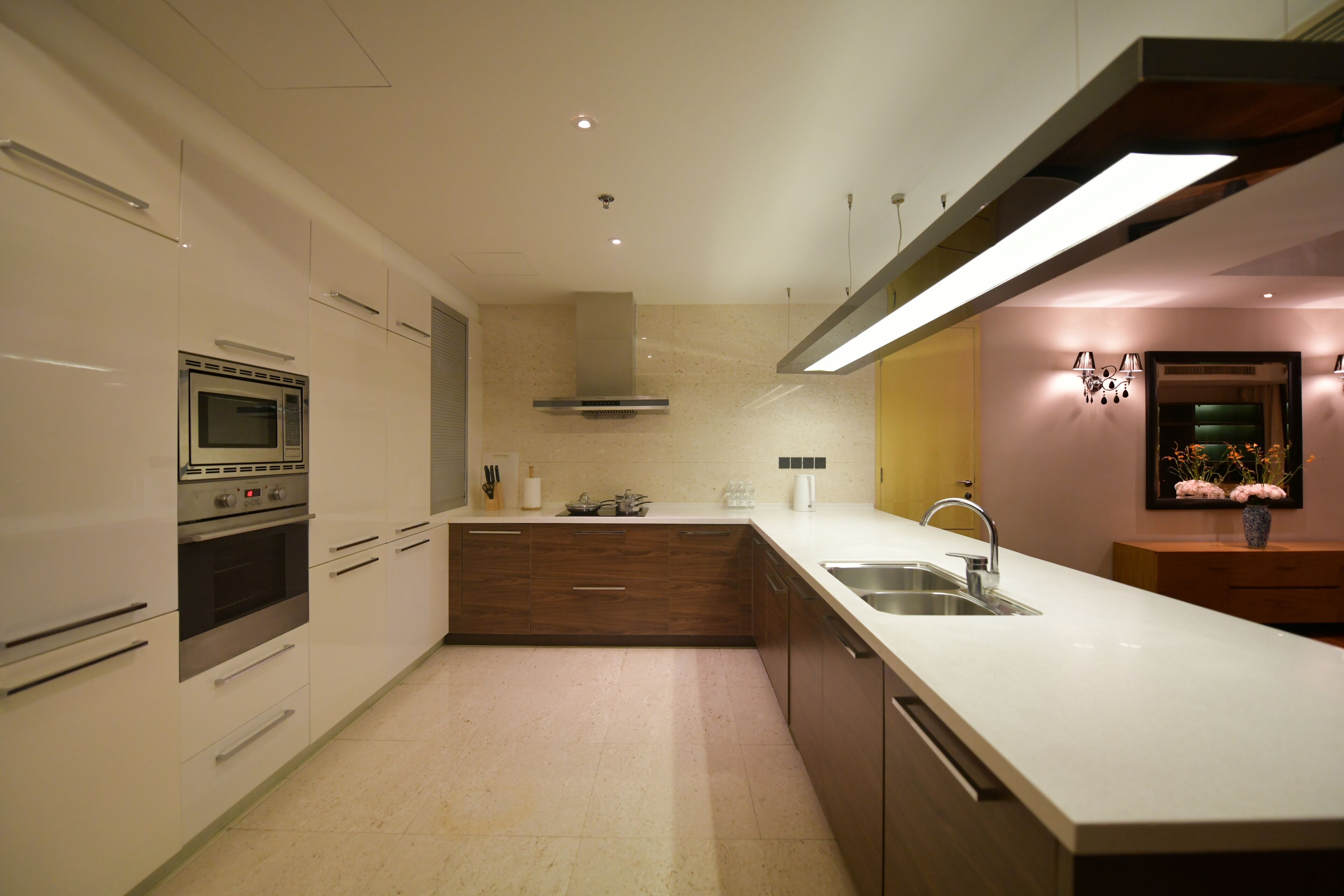 A modern kitchen with built-in appliances, a large island with a sink, and a decorative vase on the counter.