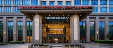 Entrada de un hotel con un gran letrero que dice 'THE SANDALWOOD BEIJING MARRIOTT EXECUTIVE APARTMENTS'.
