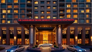 Exterior de The Sandalwood Beijing Marriott Executive Apartments, con entrada para dos coches e iluminadas ventanas.