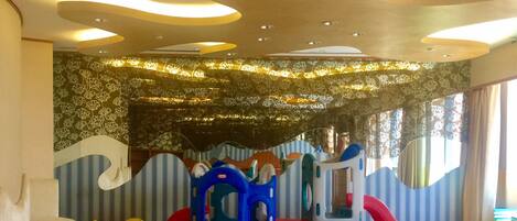 A play area with a slide, climbing structure, and soft seating.