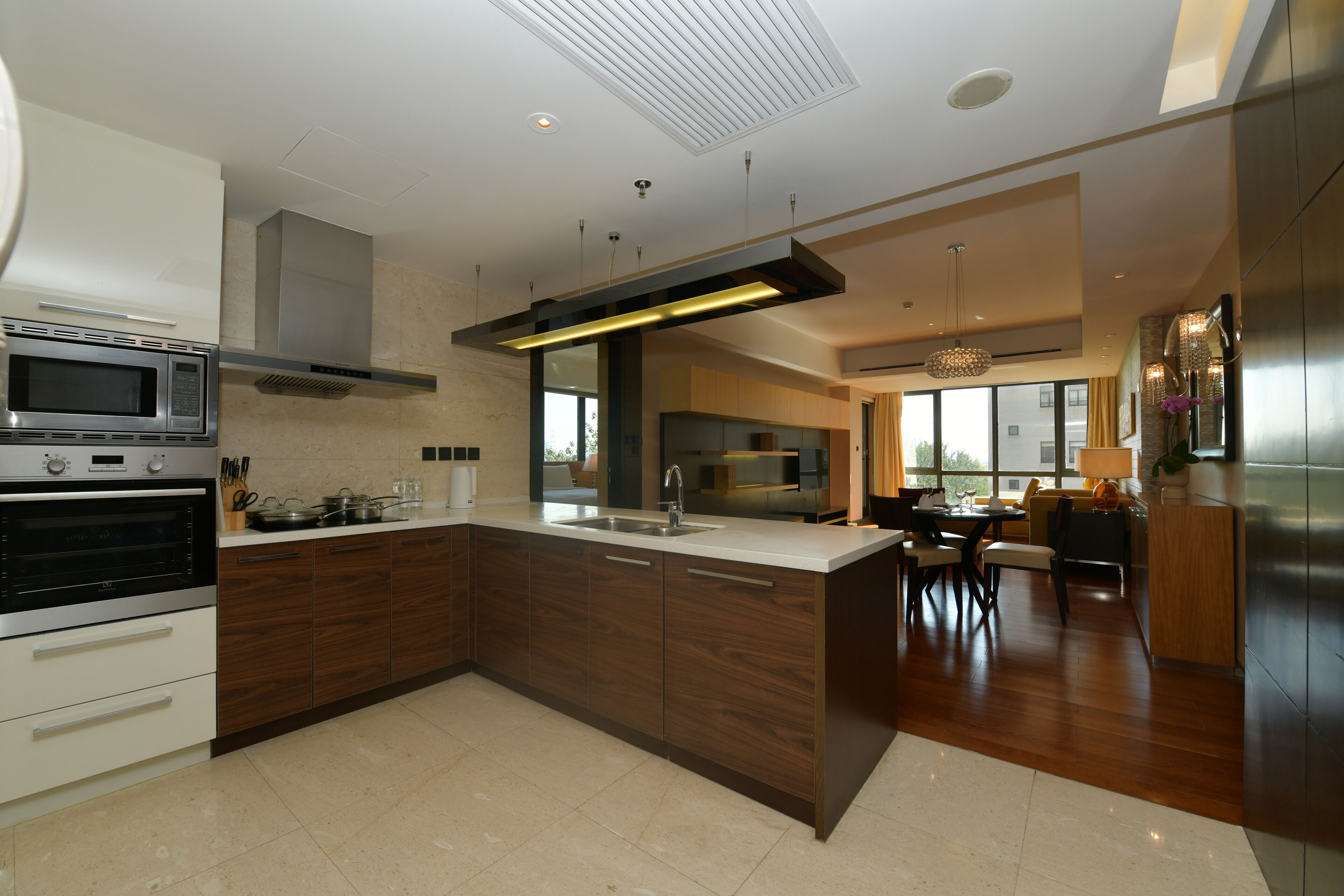 A modern kitchen with a central island, built-in oven, and stainless steel appliances.
