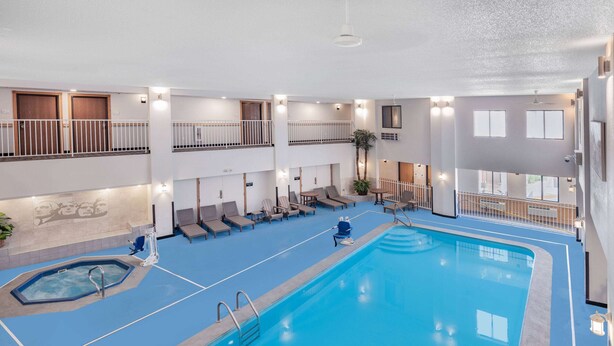 An indoor swimming pool with multiple levels, lounge chairs, and a hot tub. - Ramada by Wyndham Keystone Near Mt Rushmore (Keystone)