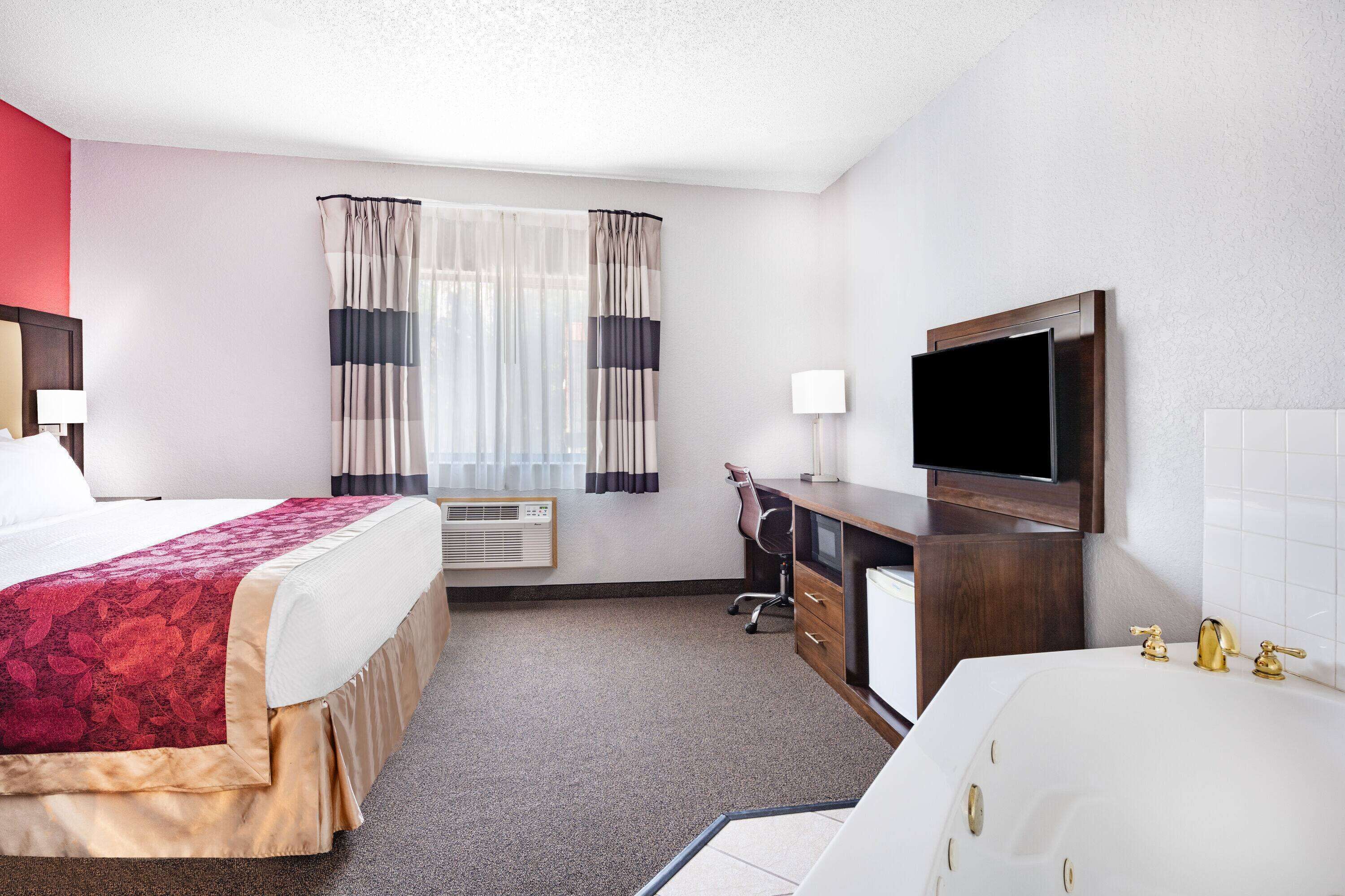 Une chambre d’hôtel équipée d’un lit, d’un bureau, d’une télévision et d’une baignoire.