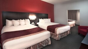 A hotel room with two beds, a red wall, a large window, and a red chair. - Ramada by Wyndham Keystone Near Mt Rushmore (Keystone)