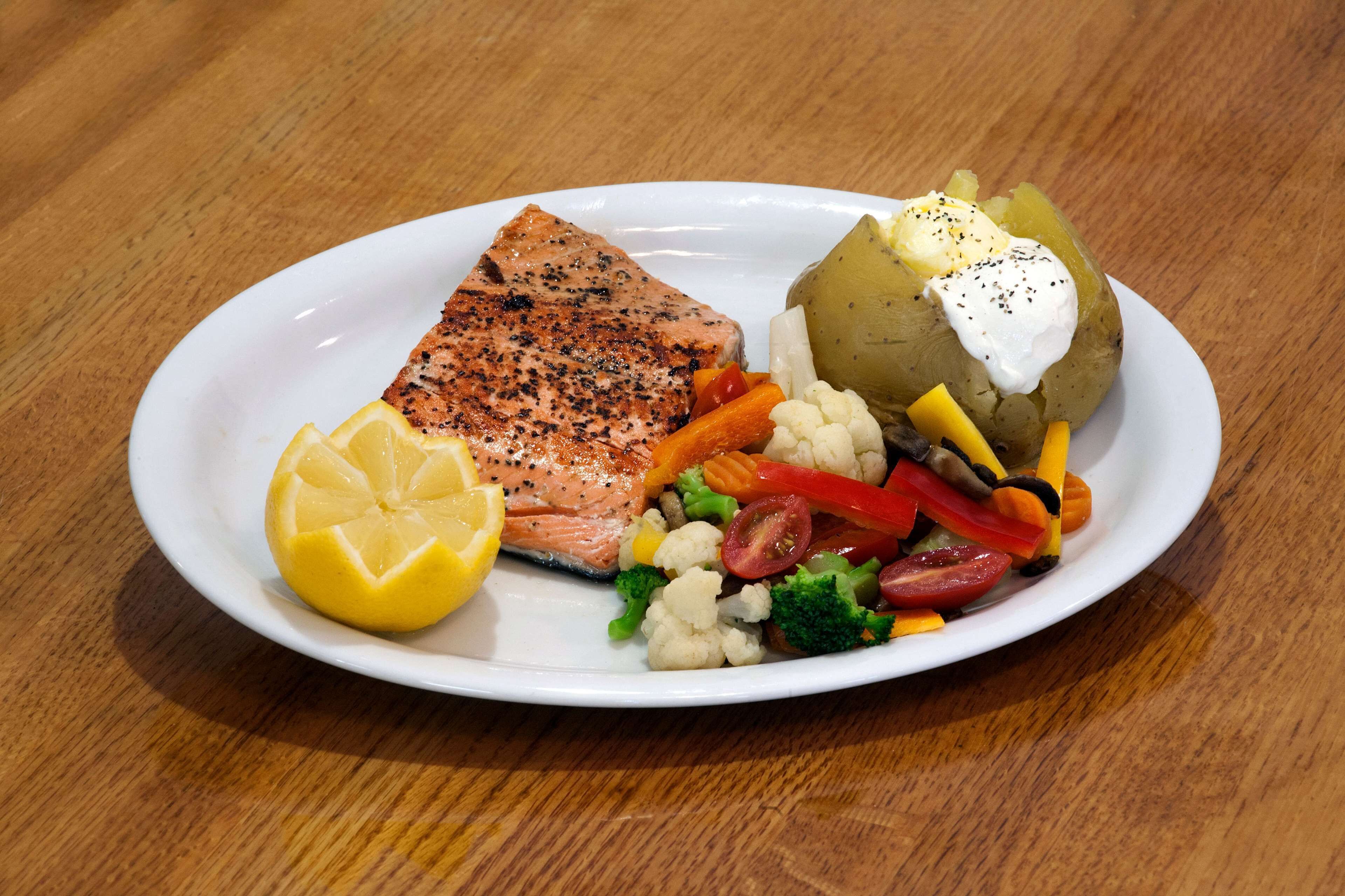 A plate with grilled salmon, lemon, and mixed vegetables.