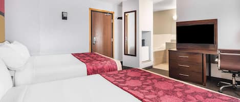 Habitación de hotel con dos camas, un escritorio, televisor y espejo.