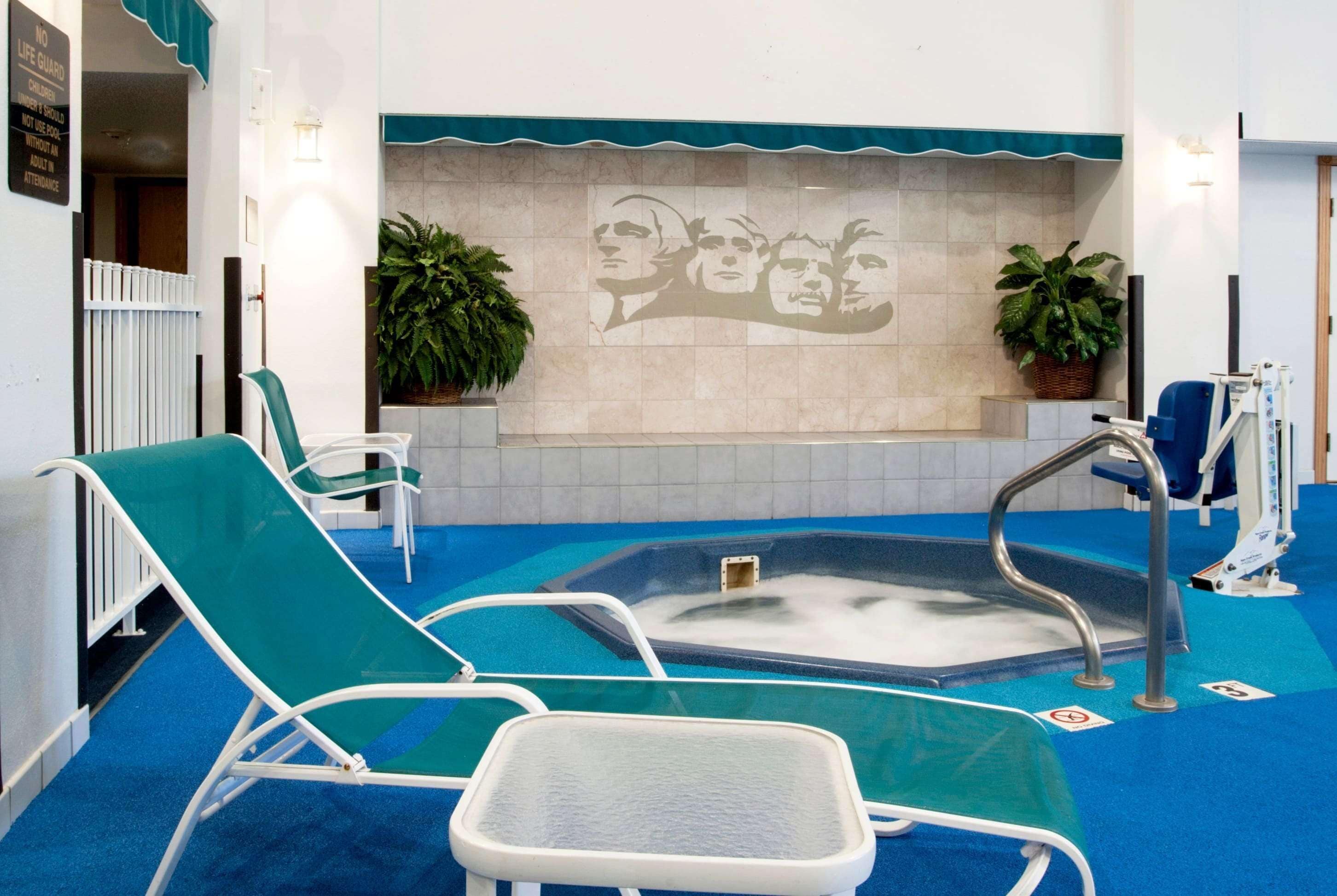 A spa area with a hot tub, lounge chairs, and a wall mural.