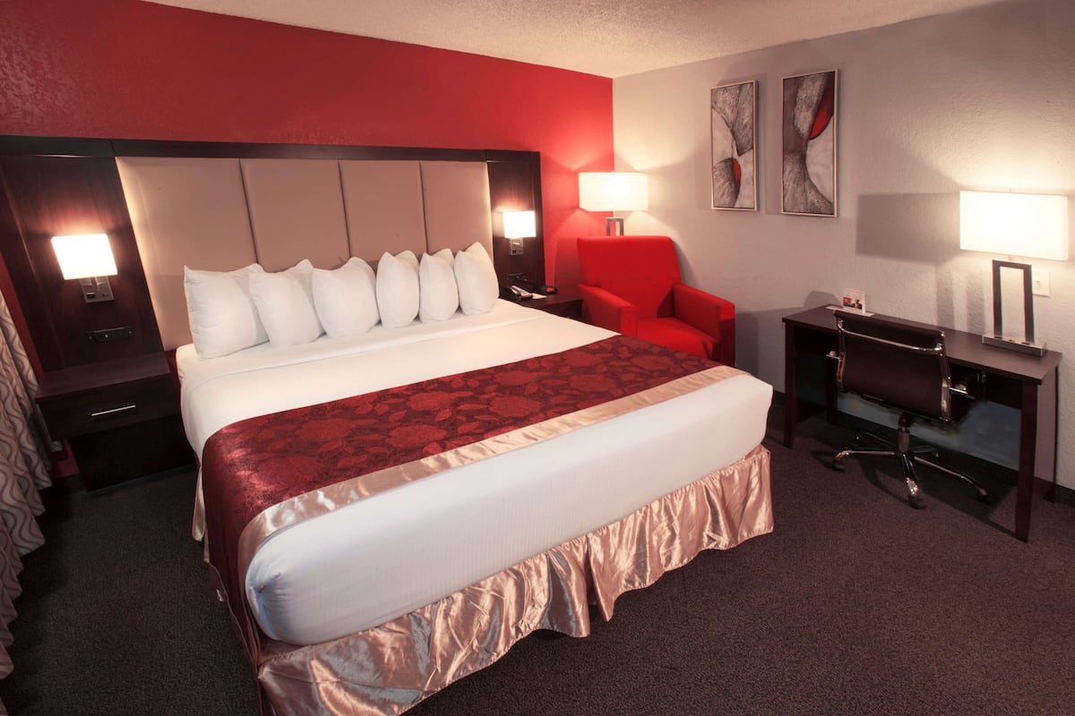 A hotel room with a large bed, a desk, a chair, and two bedside lamps.