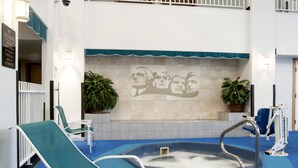 A pool area with lounge chairs, a hot tub, and a mural on the wall. - Ramada by Wyndham Keystone Near Mt Rushmore (Keystone)