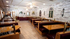 A restaurant interior with booths and tables, brick walls, and decorative elements. - Ramada by Wyndham Keystone Near Mt Rushmore (Keystone)