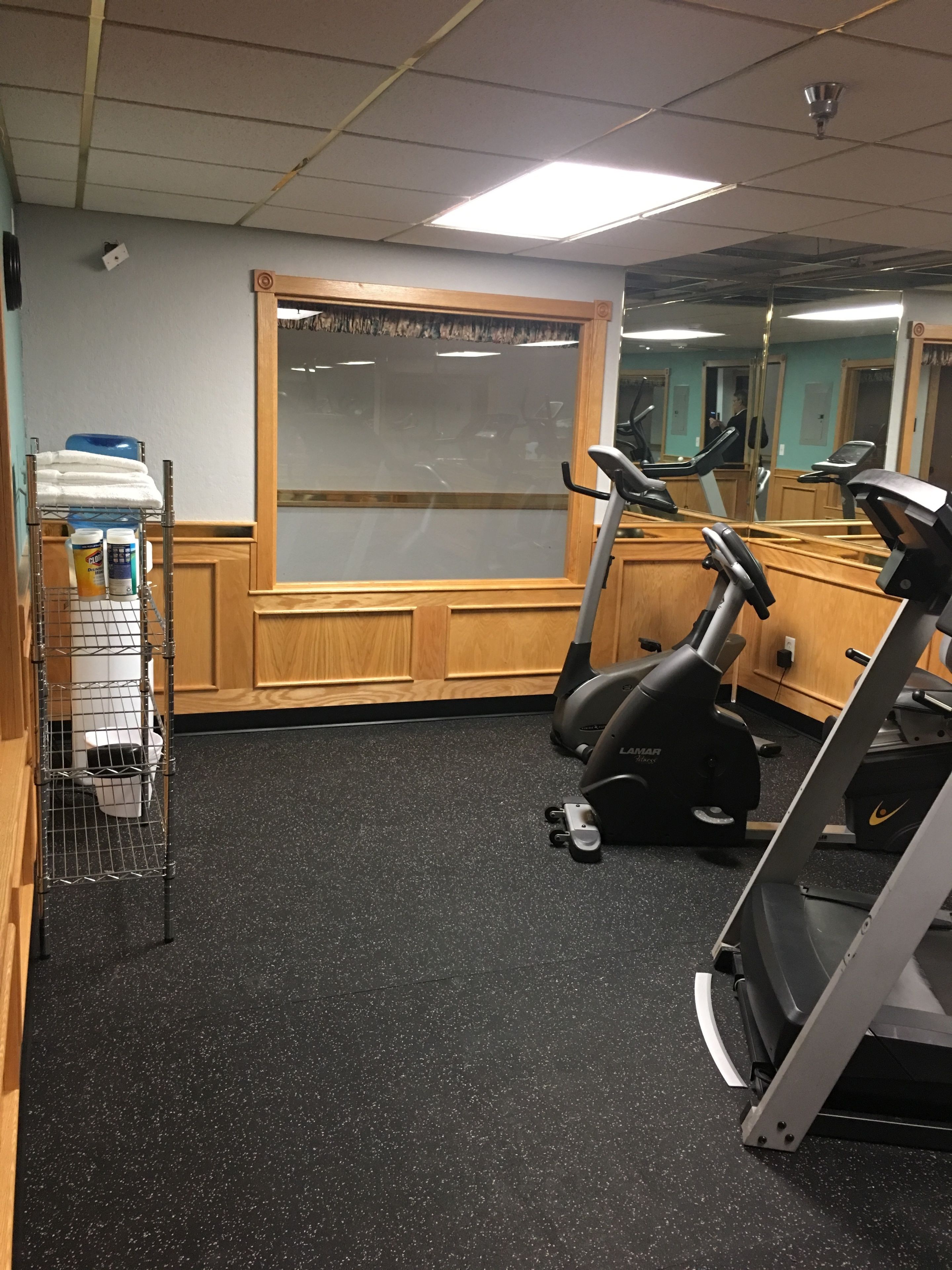 Un gimnasio con equipo de ejercicio, dispensador de agua y un espejo.