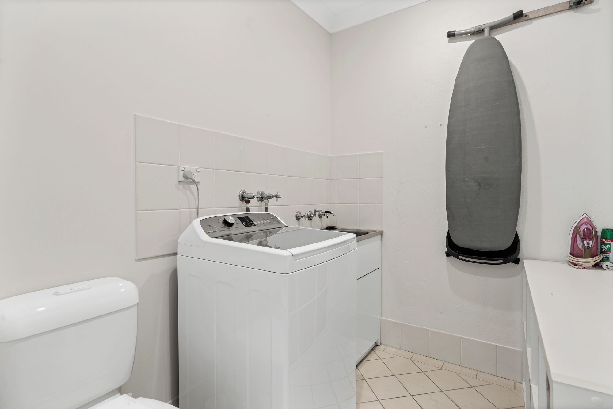 A compact bathroom with a washing machine, a toilet, and a shower area.
