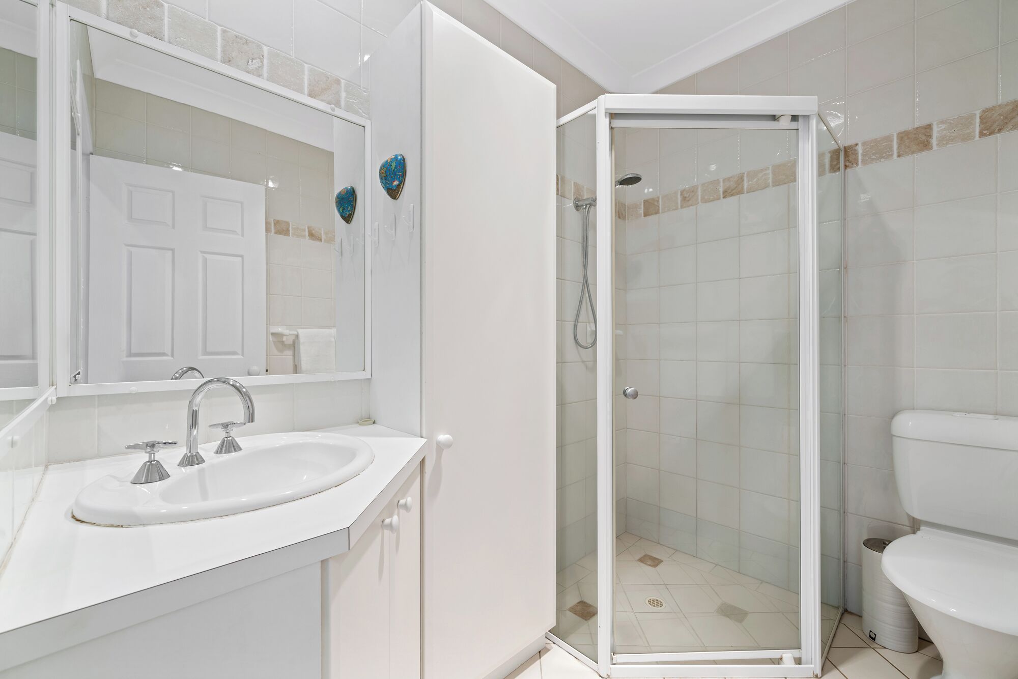 Un baño con cabina de ducha de vidrio, un lavabo blanco y un inodoro.