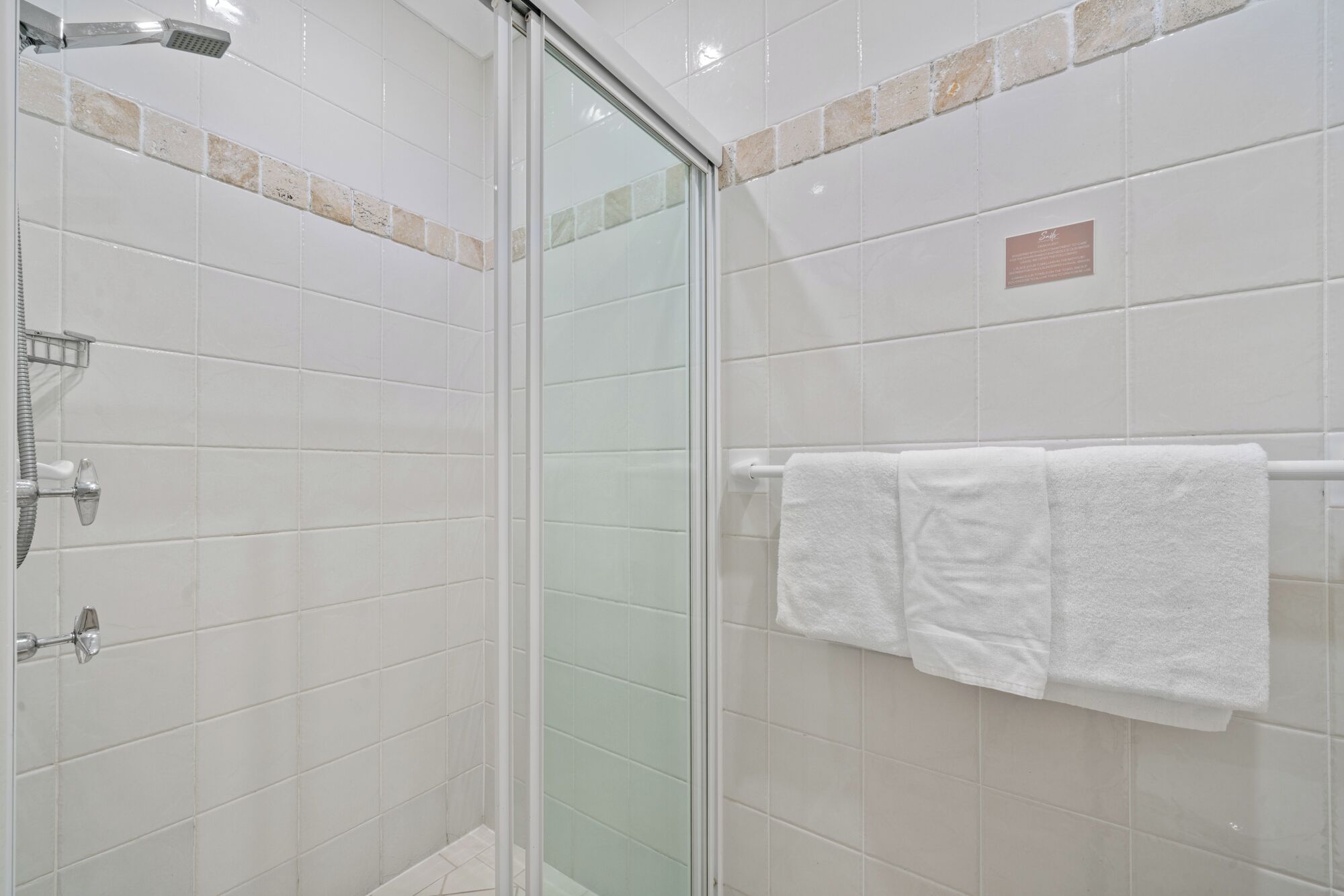 Eine Duschkabine mit Handbrause und am Wand montiertem Wasserhahn.