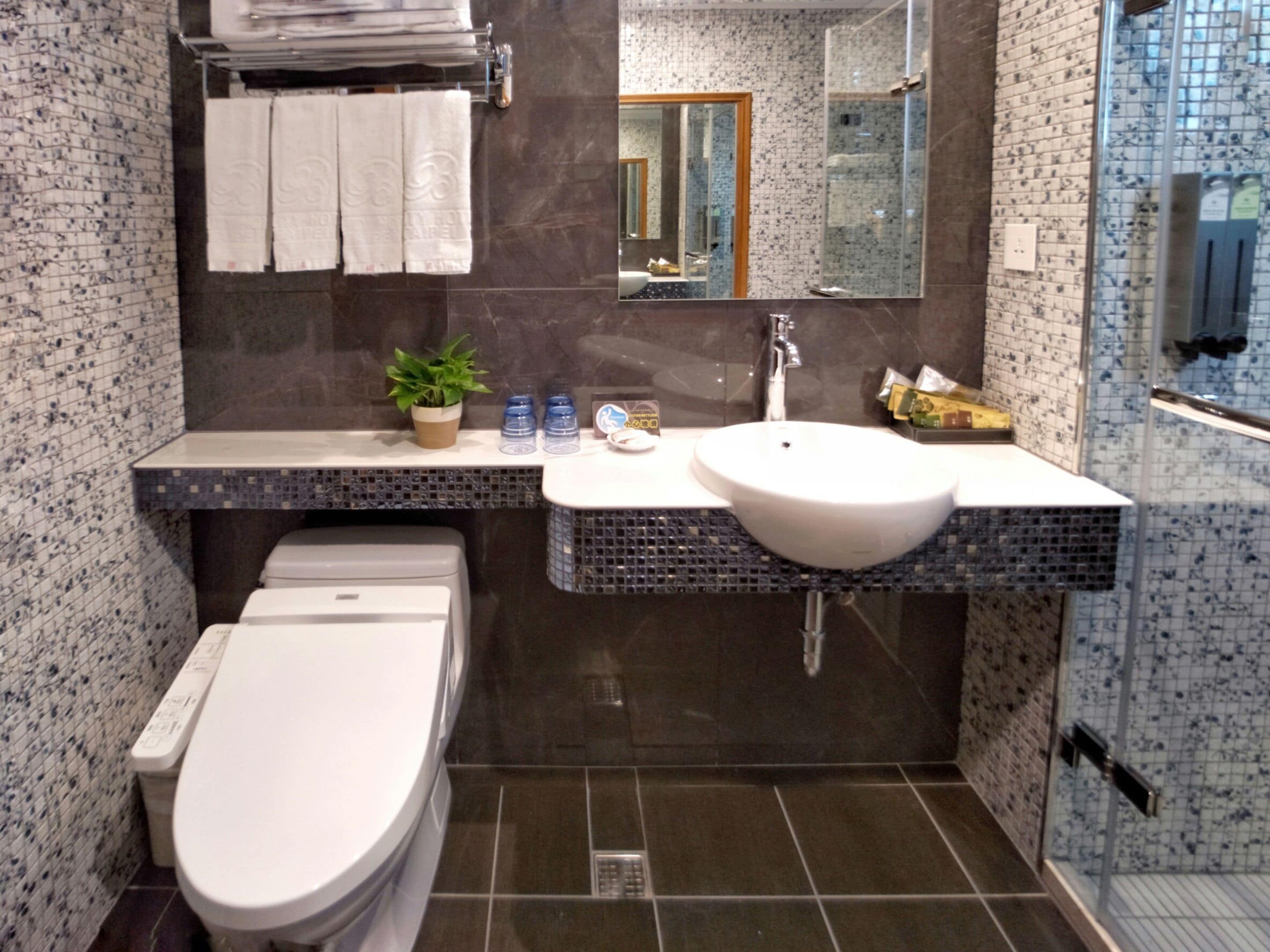 A modern bathroom with a white toilet, a sink with a mirror above it, and a shower area.