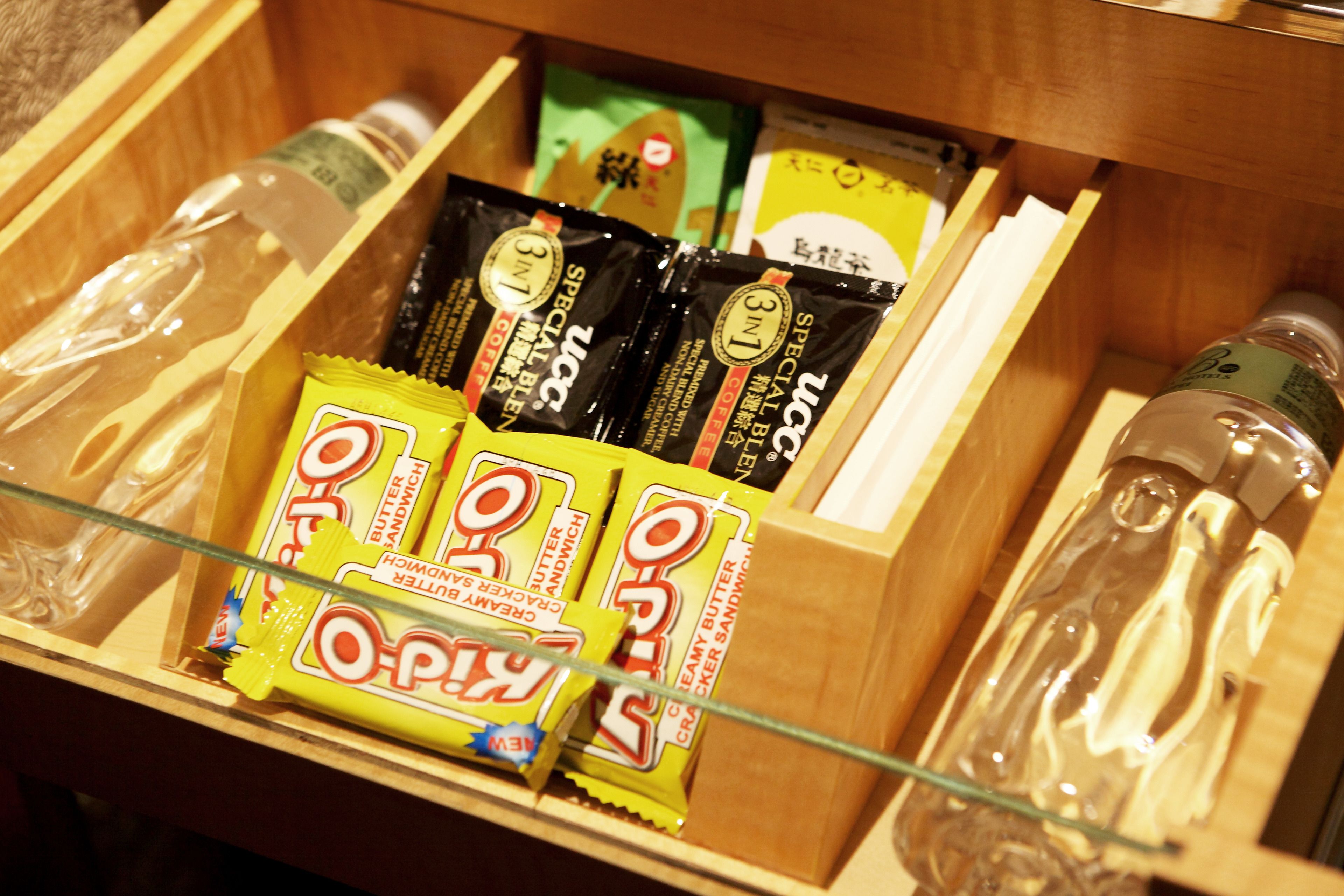A wooden drawer containing various food items, including packets of O-Pop and other snacks.
