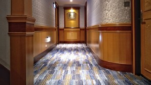 A hallway with patterned carpet, wooden paneling, and a framed picture on the wall. - Taipei Star Beauty Resort Hotel (Taipei)