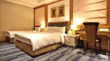 A hotel room with two beds, a desk, and a chair.