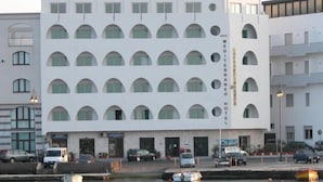 A modern hotel with a white facade, multiple balconies, and a waterfront view.