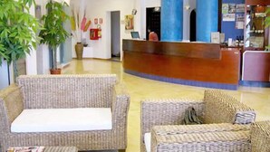 A reception area with wicker furniture, a reception desk, and potted plants.