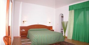Una habitación de hotel con una cama individual, una mesita de noche, una silla y una cortina verde.