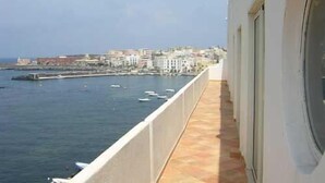 A balcony with a view of the sea and a cityscape.